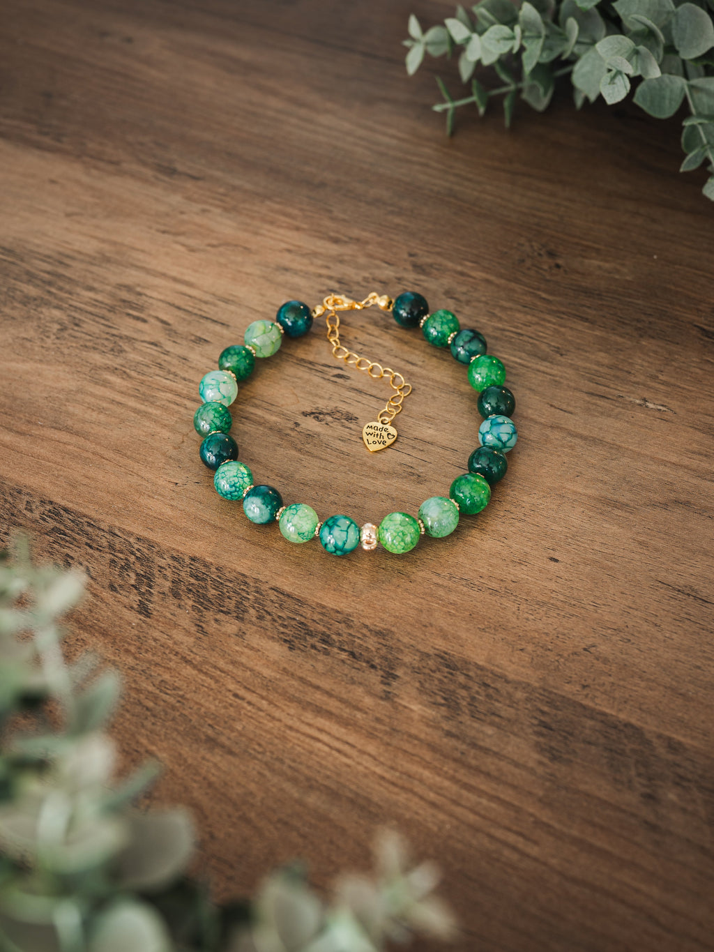 Green agate stone pet necklace with mixed forest and sage green beads and heart Made with Love charm on a wooden surface