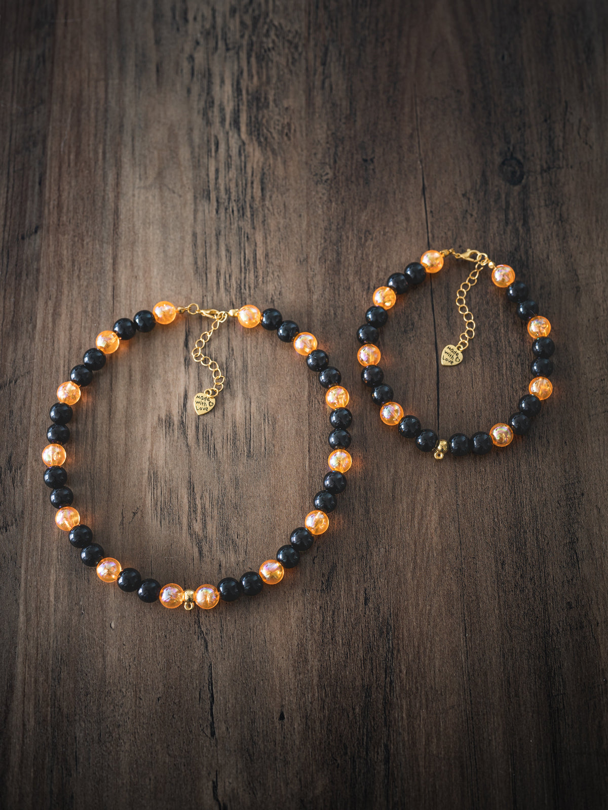 Halloween Bead Pet Necklace – black and orange beads with gold heart charm, shown in two sizes on dark wood